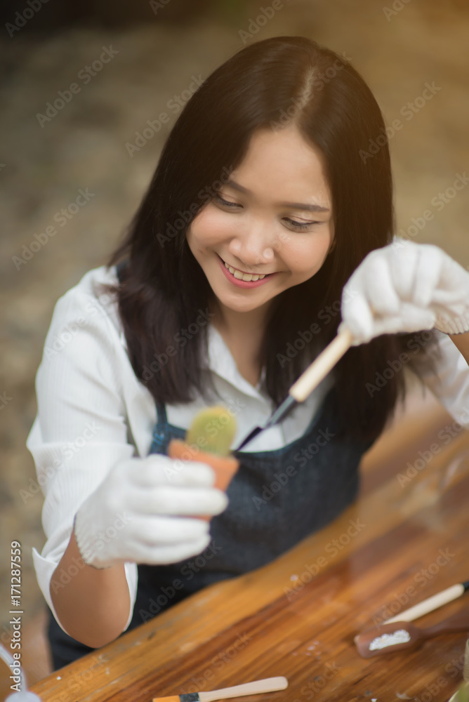 年轻的亚洲女孩在花盆里种植小仙人掌的肖像