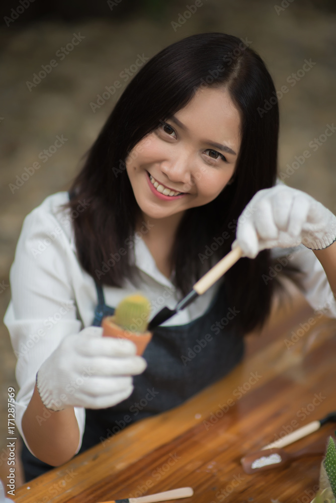 Portrait young Asian girl planting little cactus in a pot