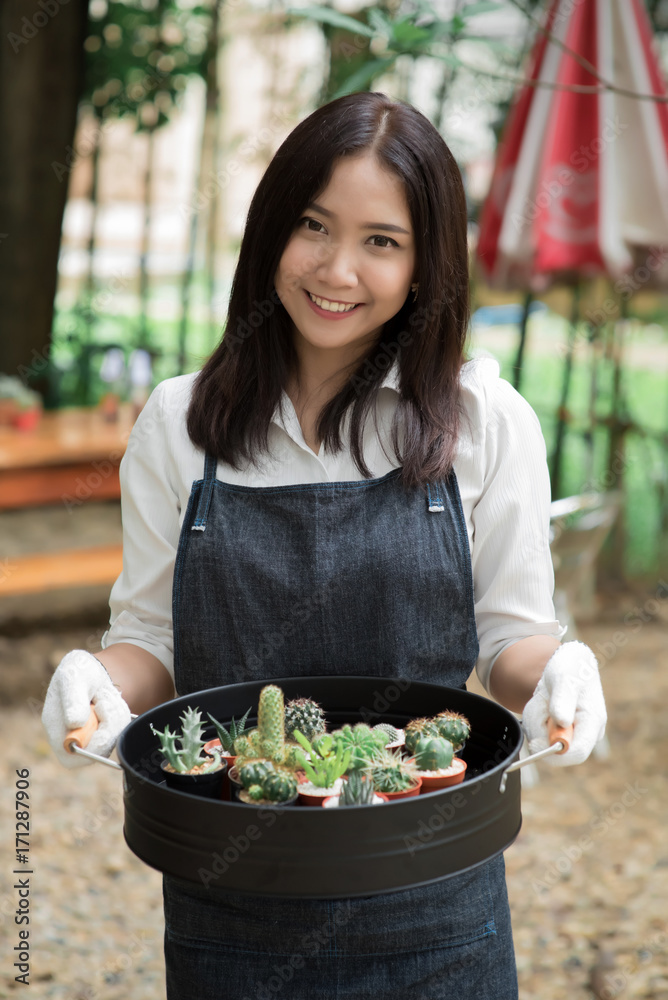 年轻的亚洲花店老板拿着一盘仙人掌出售