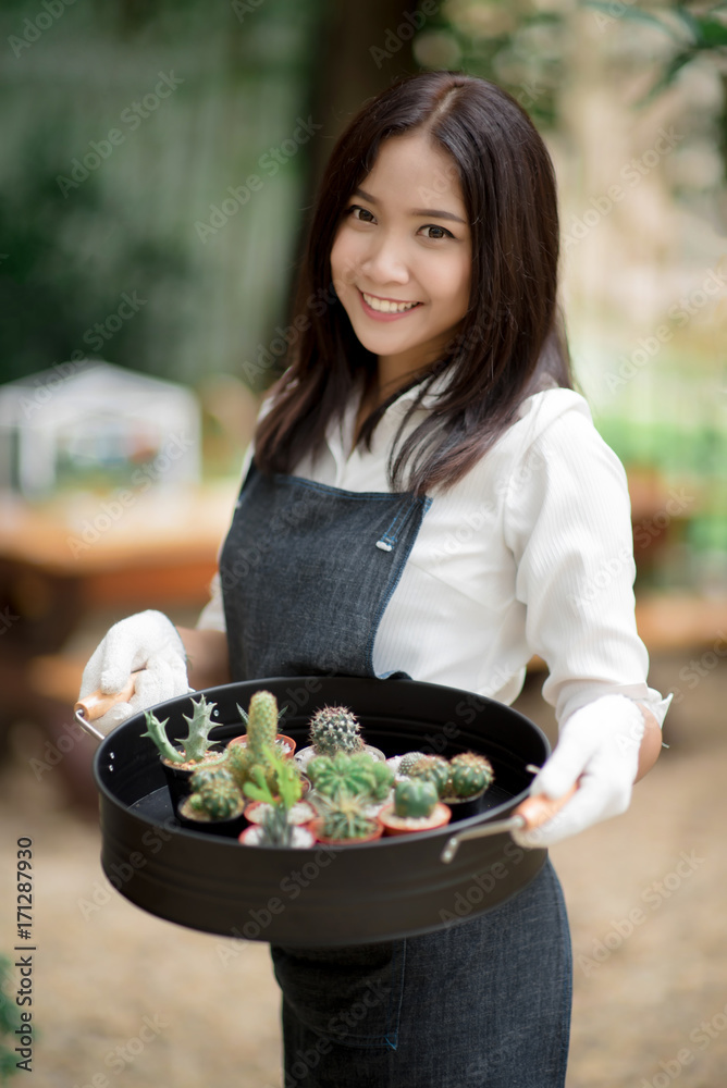 年轻的亚洲花店老板拿着一盘仙人掌出售