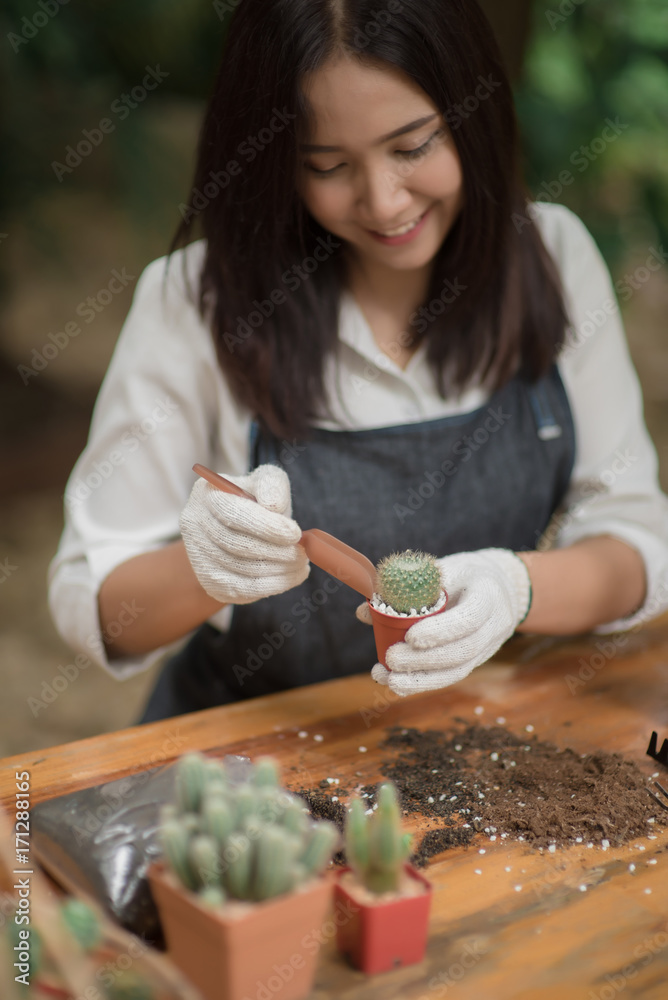 年轻的亚洲女孩在花盆里种植小仙人掌的肖像