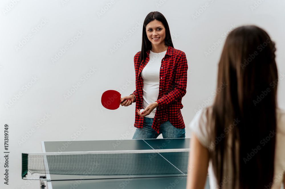 Two beautiful girls playing table tennis.