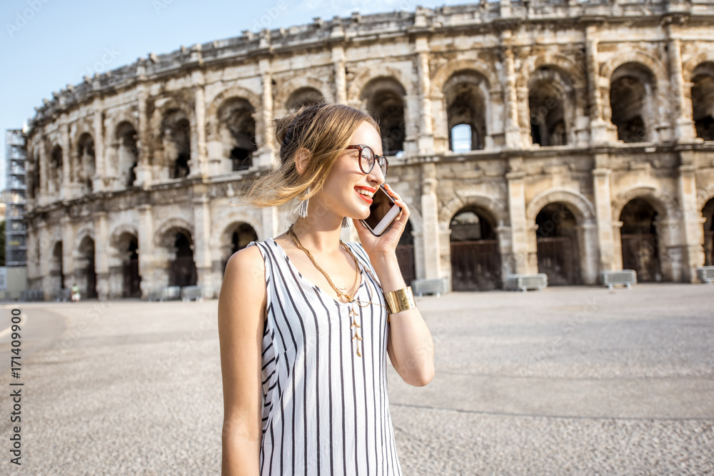 Lifestyle portrait of a young businesswoman walking near old roman amphitheatre in Nimes city, Franc