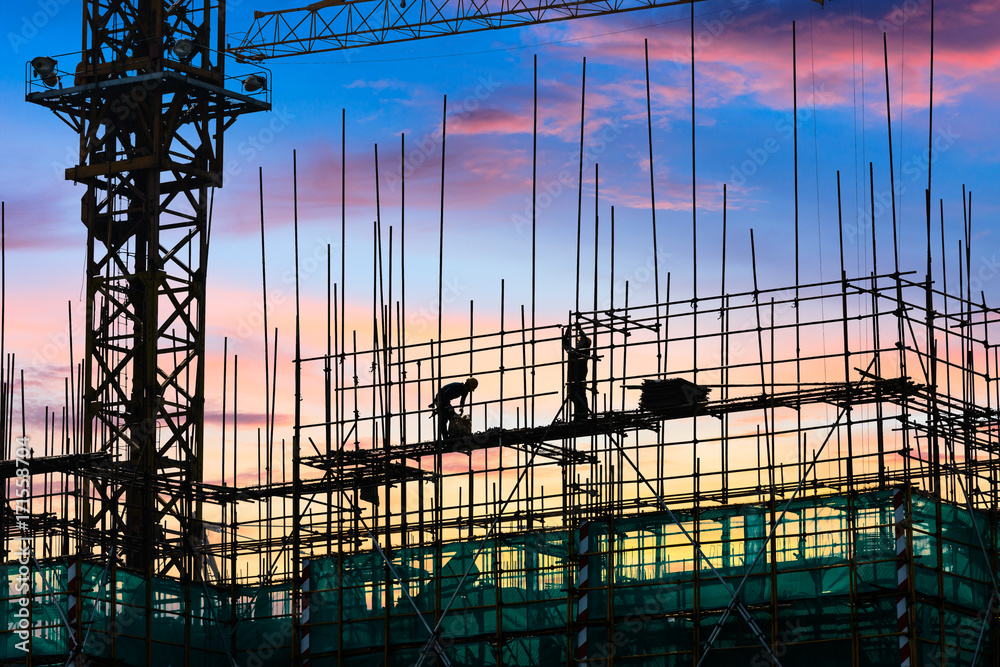 Construction site with crane and workers at sunset