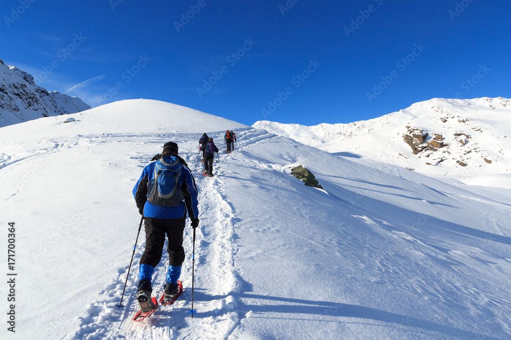 一群人穿着雪鞋徒步旅行，在奥地利斯塔拜阿尔卑斯山欣赏蓝天的山雪全景