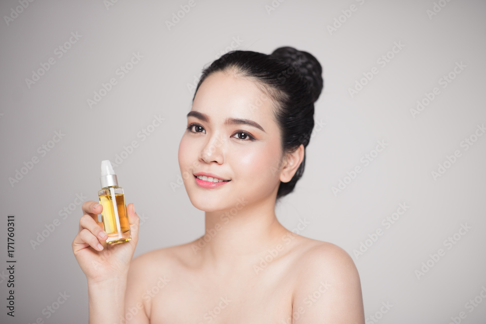 Beauty concept. Asian pretty woman with perfect skin holding oil bottle