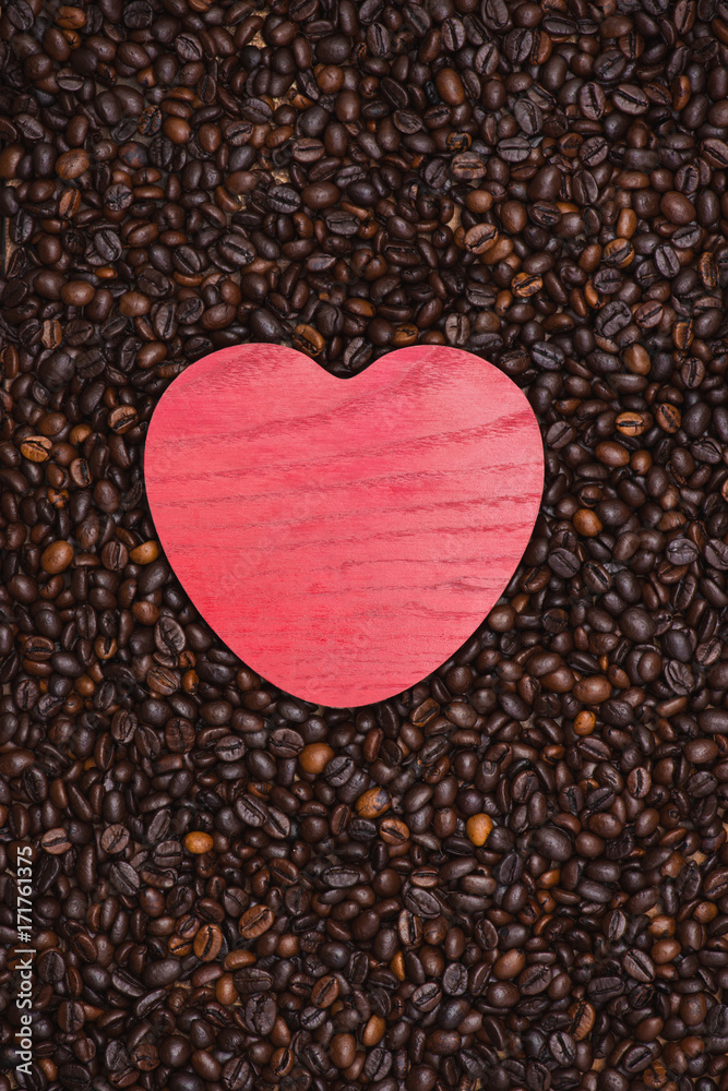 Red wooden heart shape on coffee beans background.