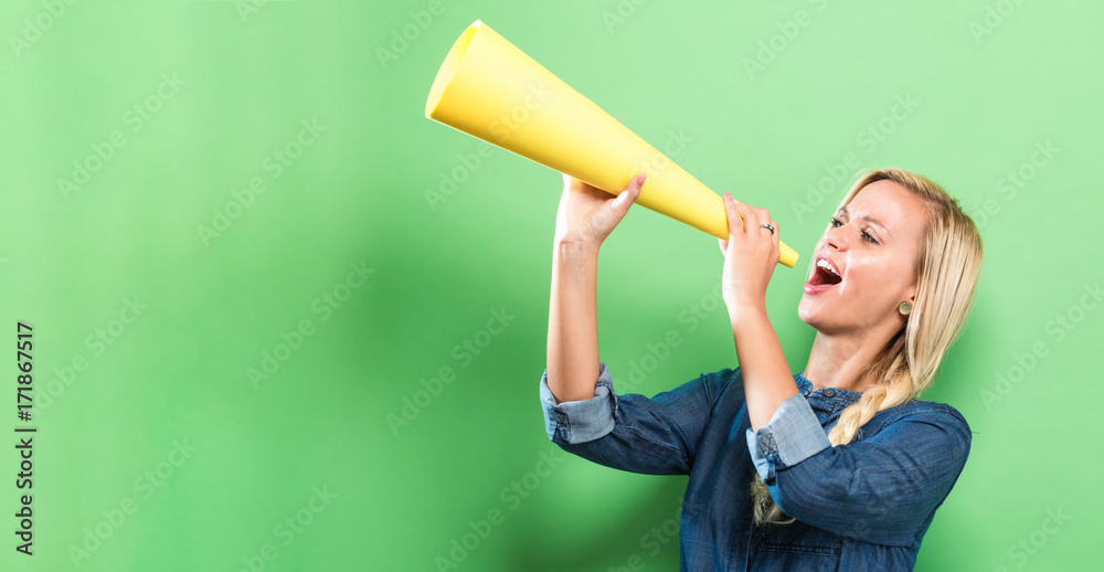 Young woman holding a paper megaphone on a solid background