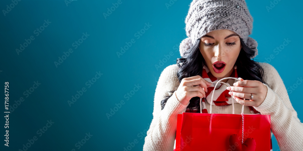 Happy young woman holding a shopping bag on a solid background