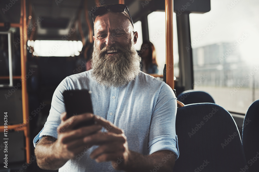 Laughing mature man reading texs while riding on a bus