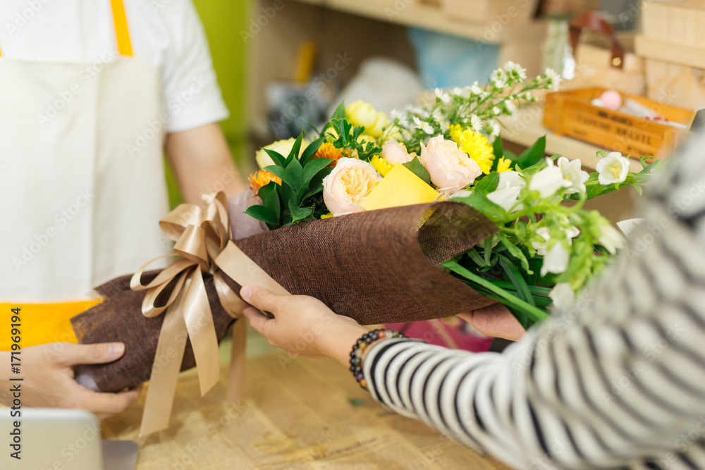 Florist giving bouquet of flower to woman in flower shop