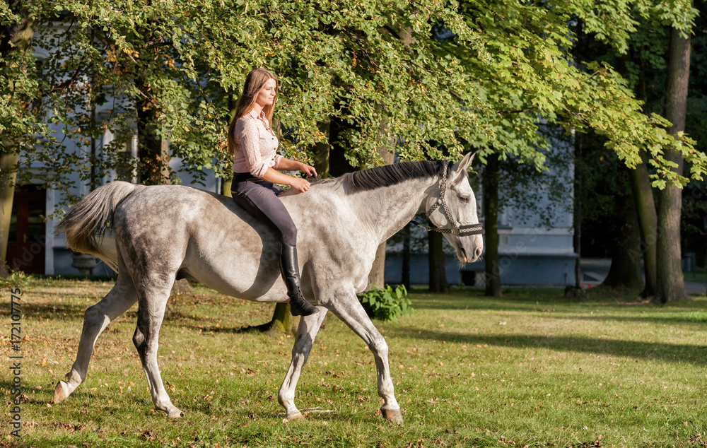 Woman riding a horse in forest or park