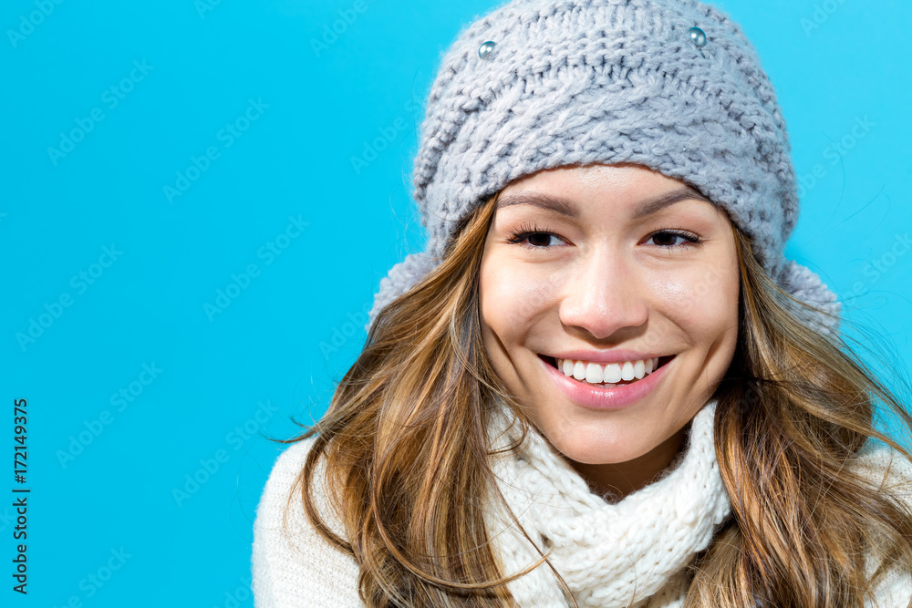 Happy young woman in winter clothes on a blue background