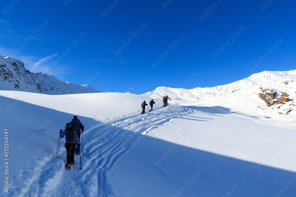 一群人穿着雪鞋徒步旅行，在奥地利斯塔拜阿尔卑斯山欣赏蓝天的高山雪全景