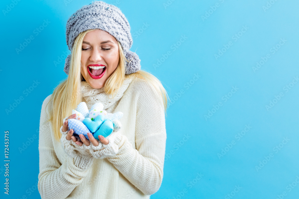 Happy young woman holding heart cushions on a blue background