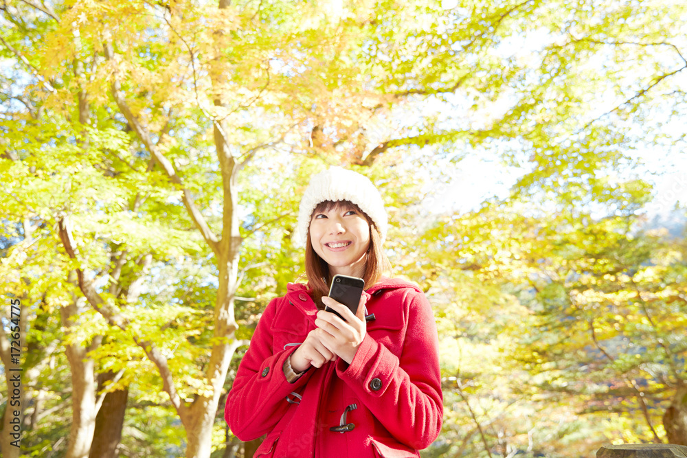 秋の紅葉の中の女性　スマートフォン