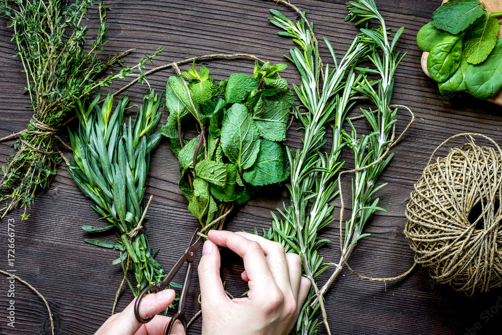 sage and thyme, mint, estragon on wooden background with hands