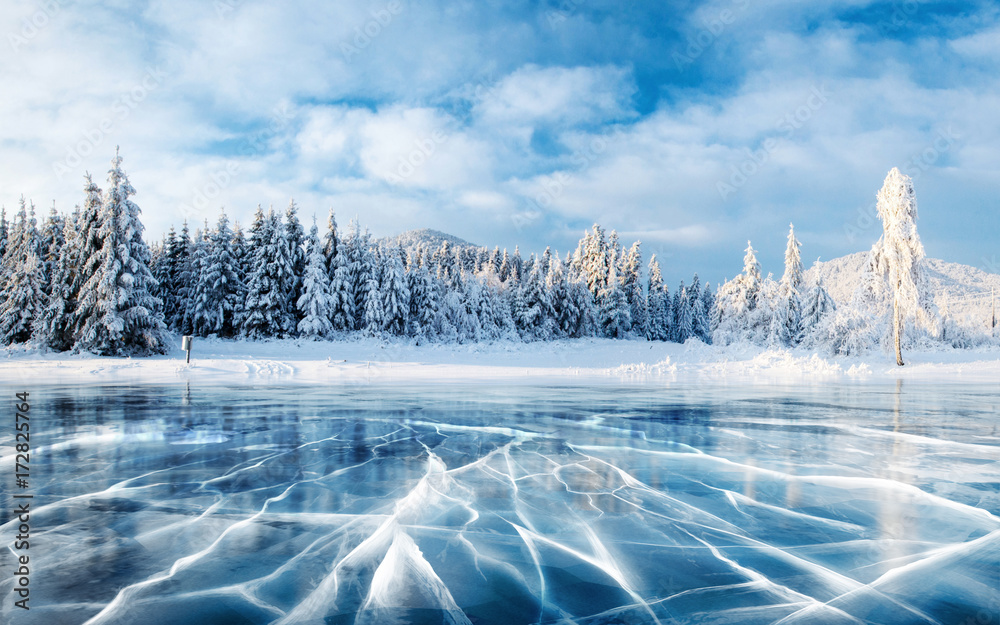 Blue ice and cracks on the surface of the ice. Frozen lake under a blue sky in the winter. The hills