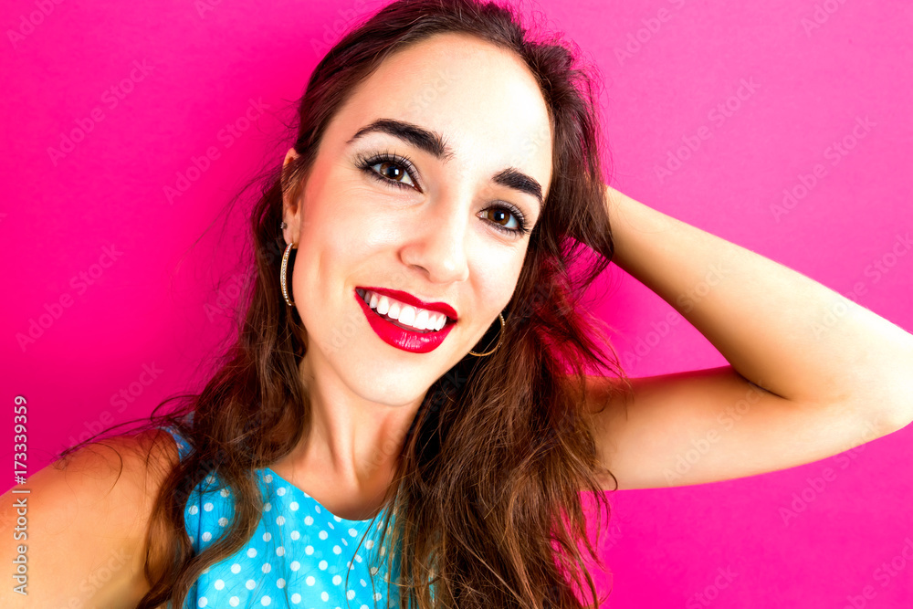 Young woman taking a selfie on a pink background