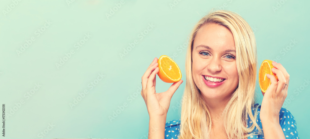 Happy young woman holding oranges on a blue background