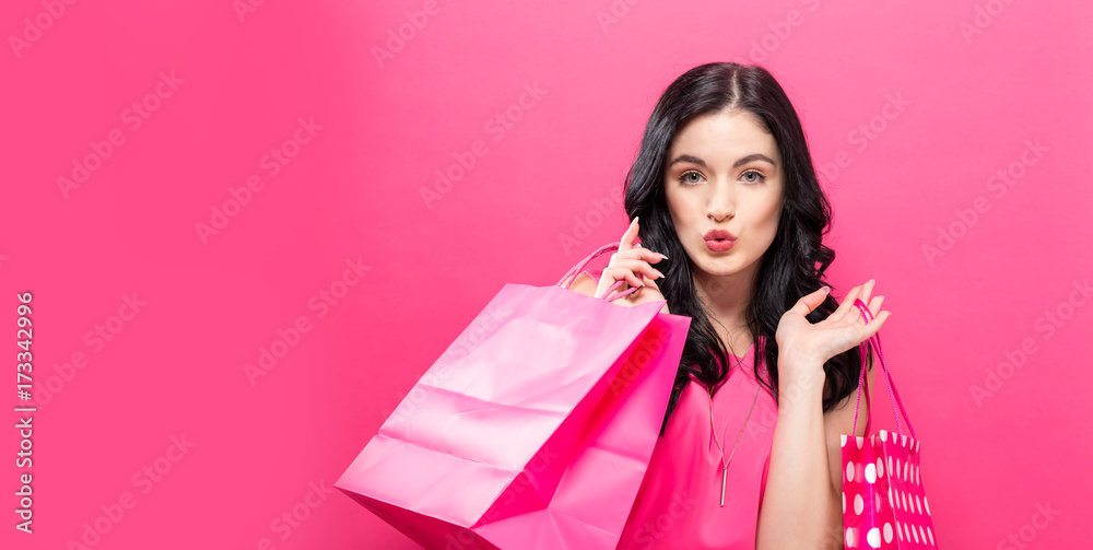 Happy young woman holding shopping bags on a solid background