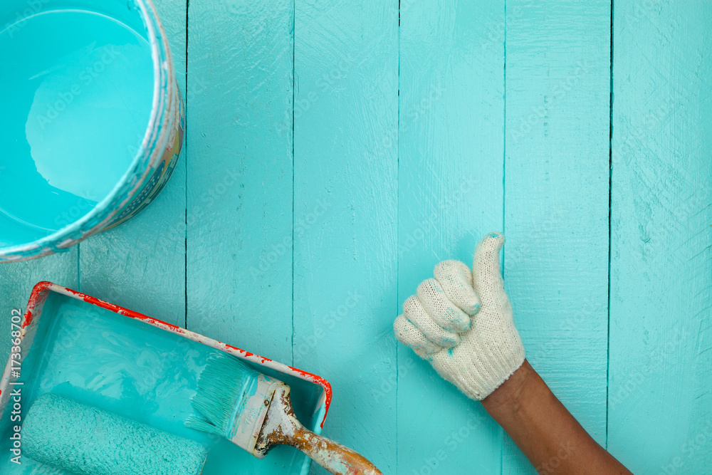 male hand showing thumbs up with painting blue color on wooden table.