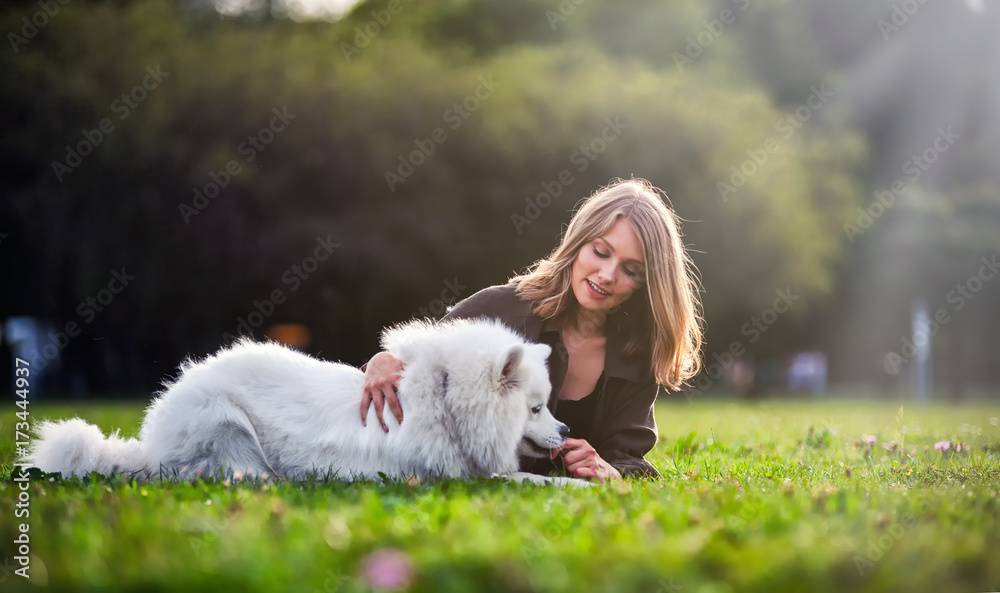 Pretty girl playing with dog on grass at the park