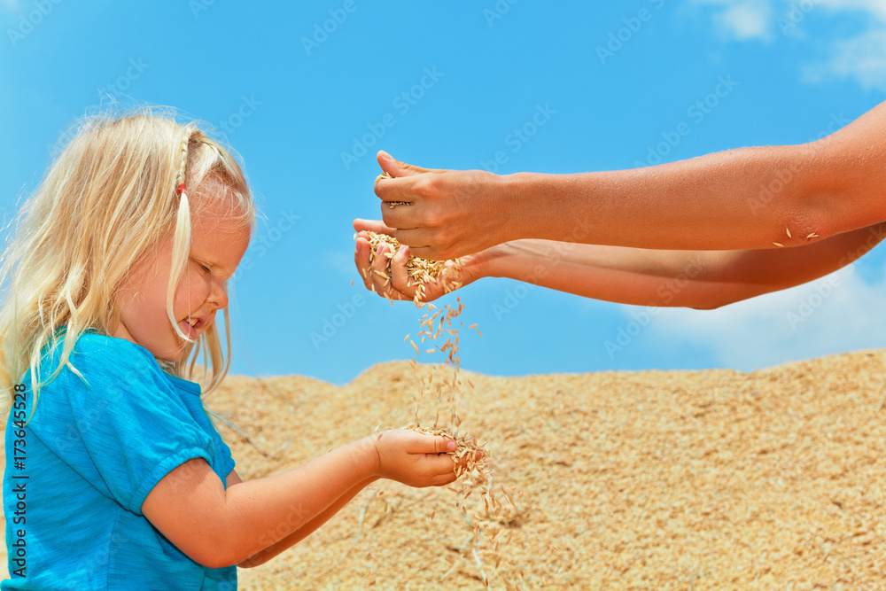 Family country plantation holidays with kids. Happy child with mother sit on heap of farm grains cro