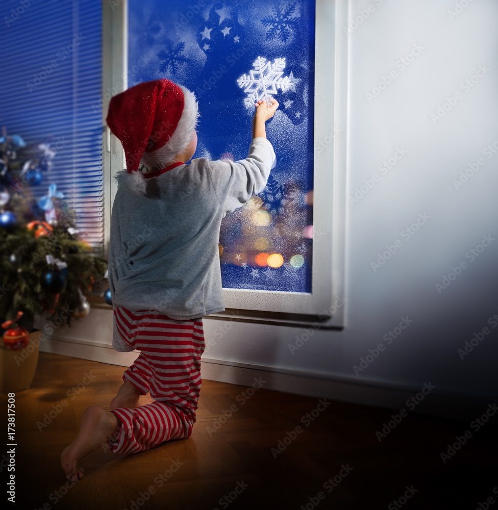 Little boy with snowflake decorating window