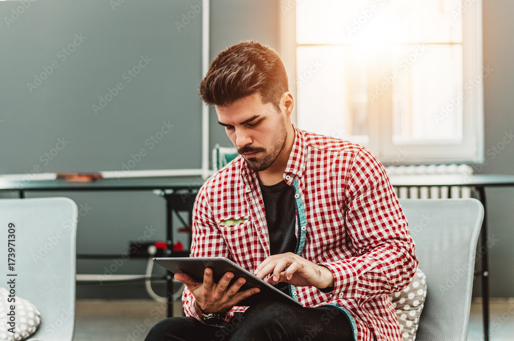 Happy bearded college student man using digital tablet pc.