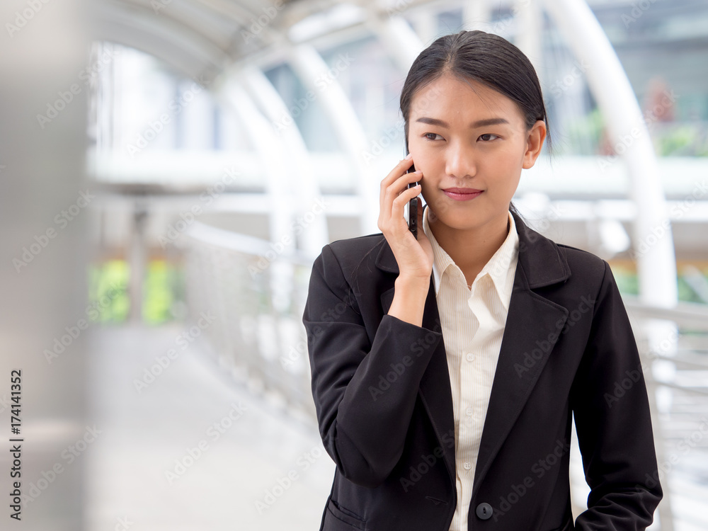 Portrait young Asian businesswoman 20-30s holding smart phone in formal suit at the modern city