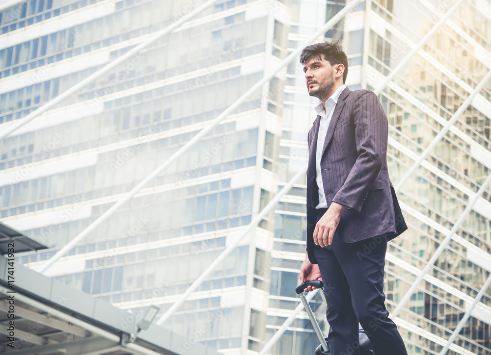 Successful businessman in suit standing outdoor in modern city, looking for new project for business