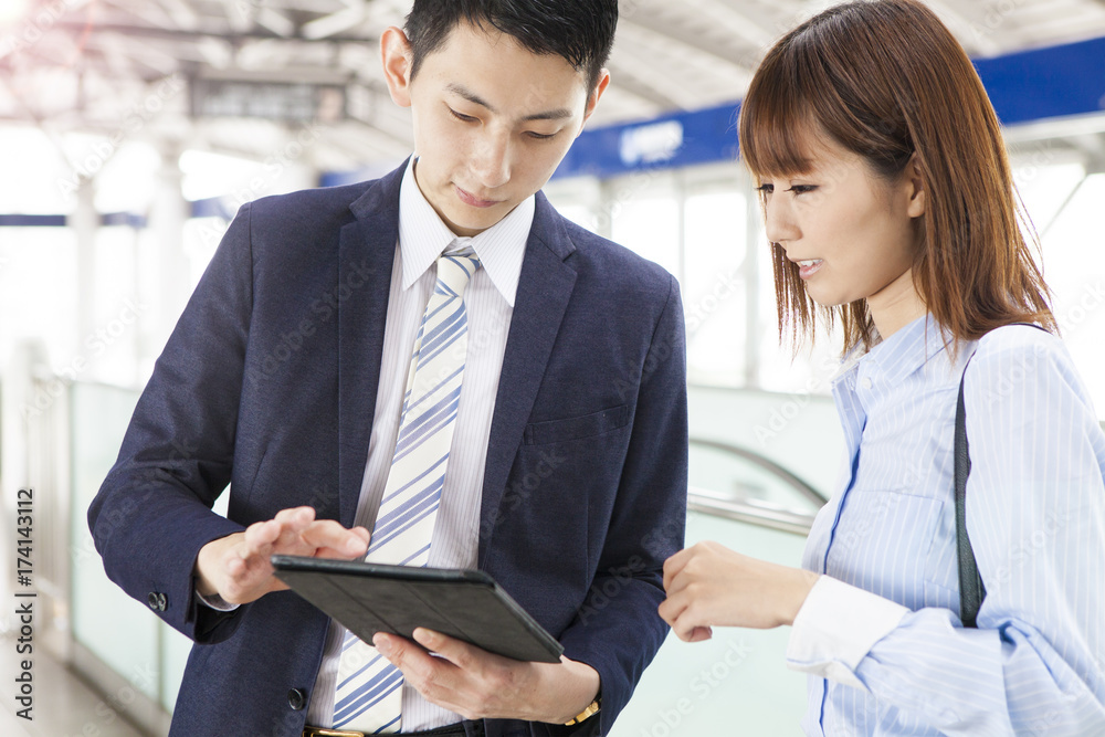 Business couple speaks while using tablet at the station home