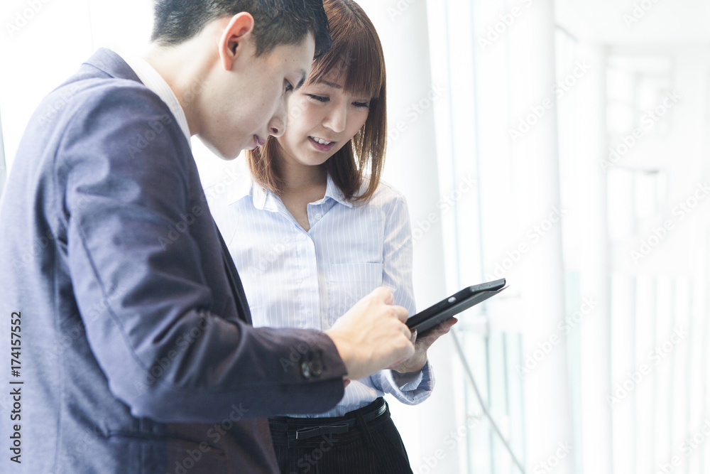 Business couple talking while watching the tablet