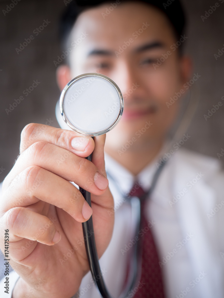 Smiling Asian doctor in uniform holding stethoscope(close up) for medical concept