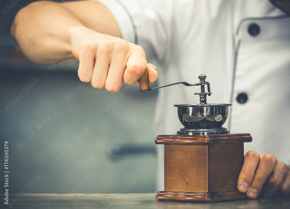 Close up baristas hand rolling coffee grinder, vintage tone