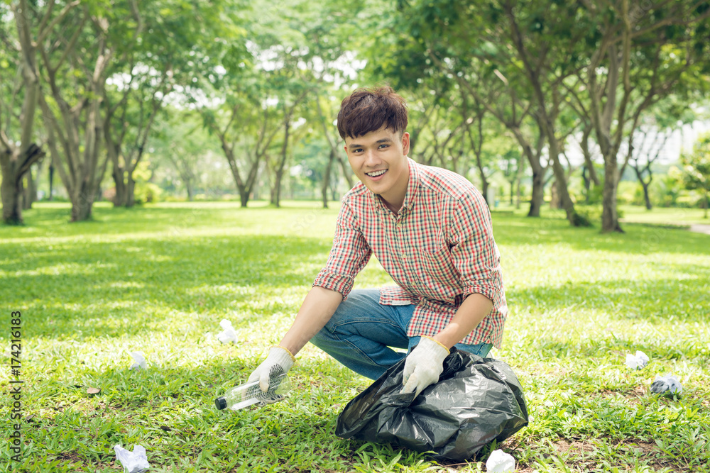 Asian man picking up plastic household waste in park