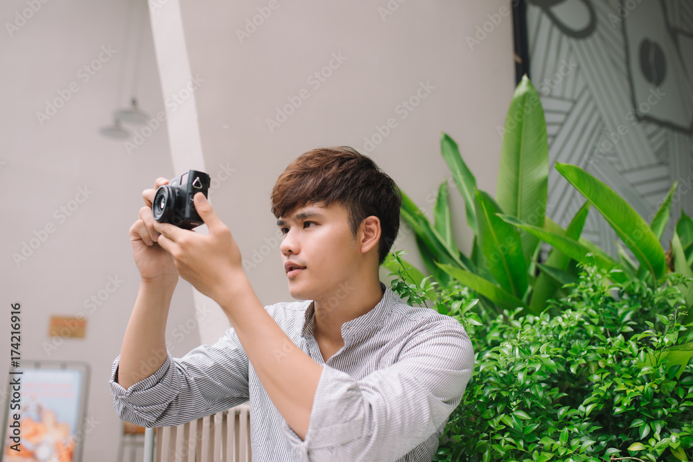 Young man photographer taking picture sitting at table in coffee shop