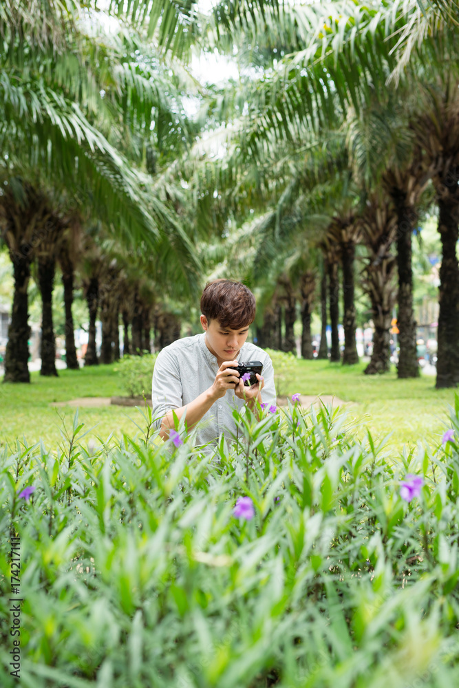 Young asian man photographer taking picturein park