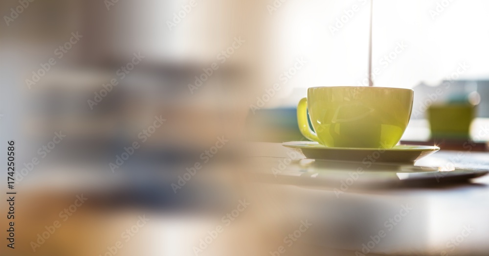 Green coffee cup on desk and blurry office transition