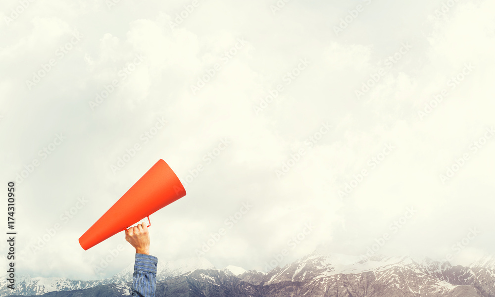 Hand of man holding paper trumpet against natural landscape background