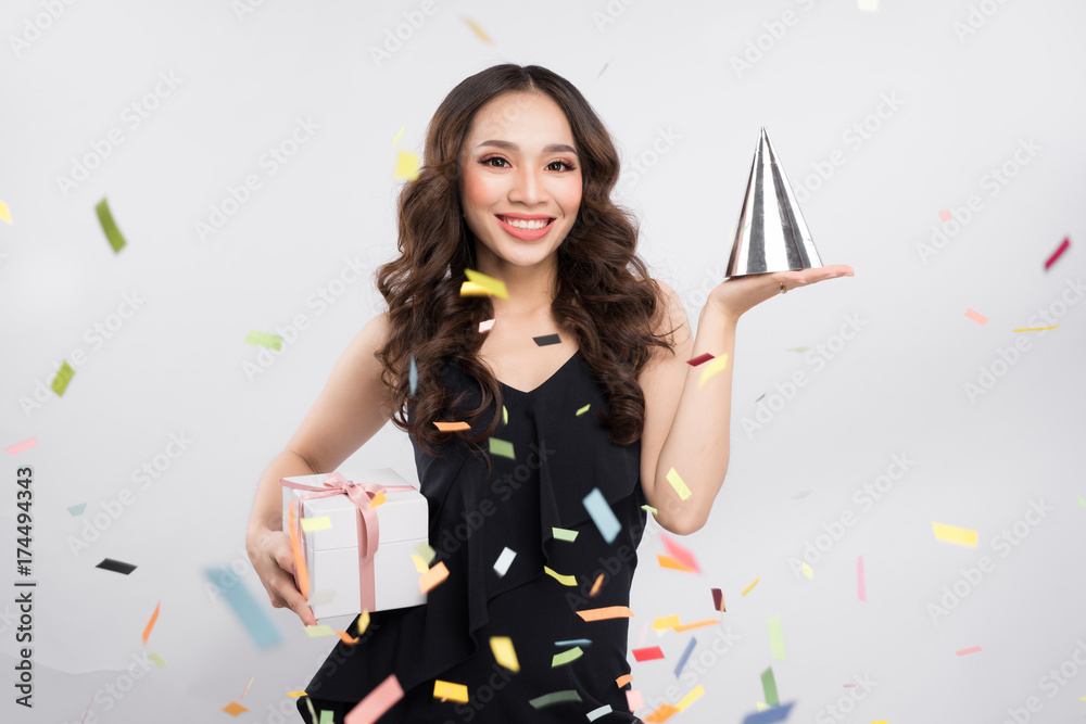 Happy asian woman celebrating holding gift box with confetti on white background