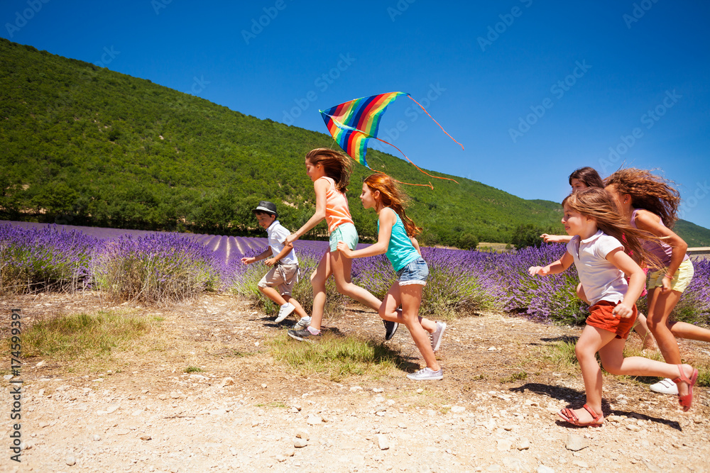 Happy children flying colorful kite in summer