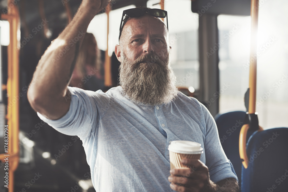 Mature man drinking coffee while standing on a bus