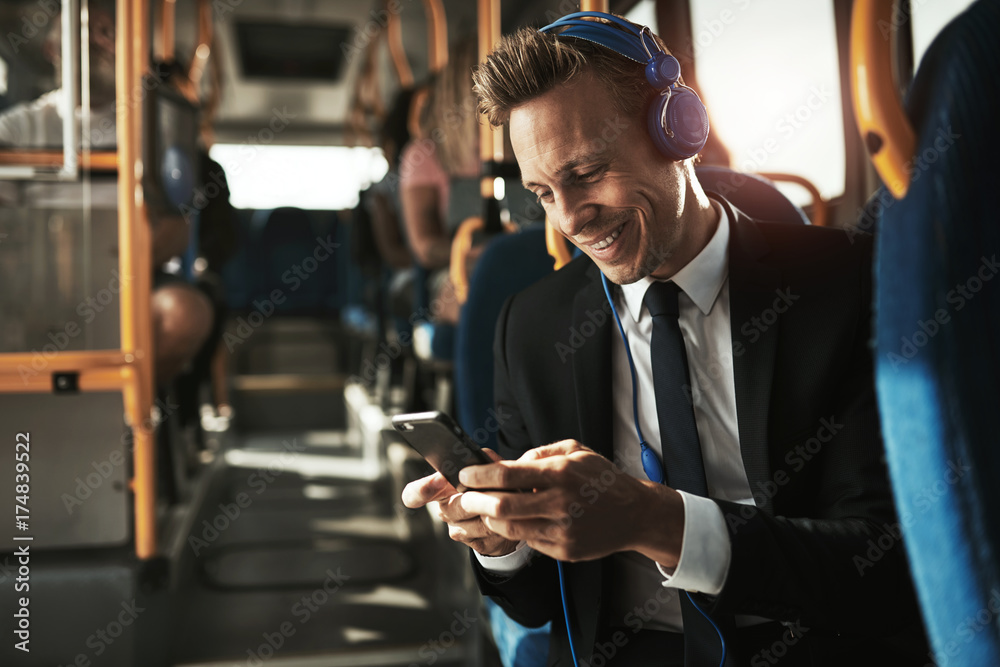 Smiling young businessman listening to music on his morning commute