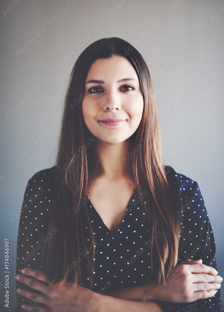 Young businesswoman smiling while standing alone with her arms crossed