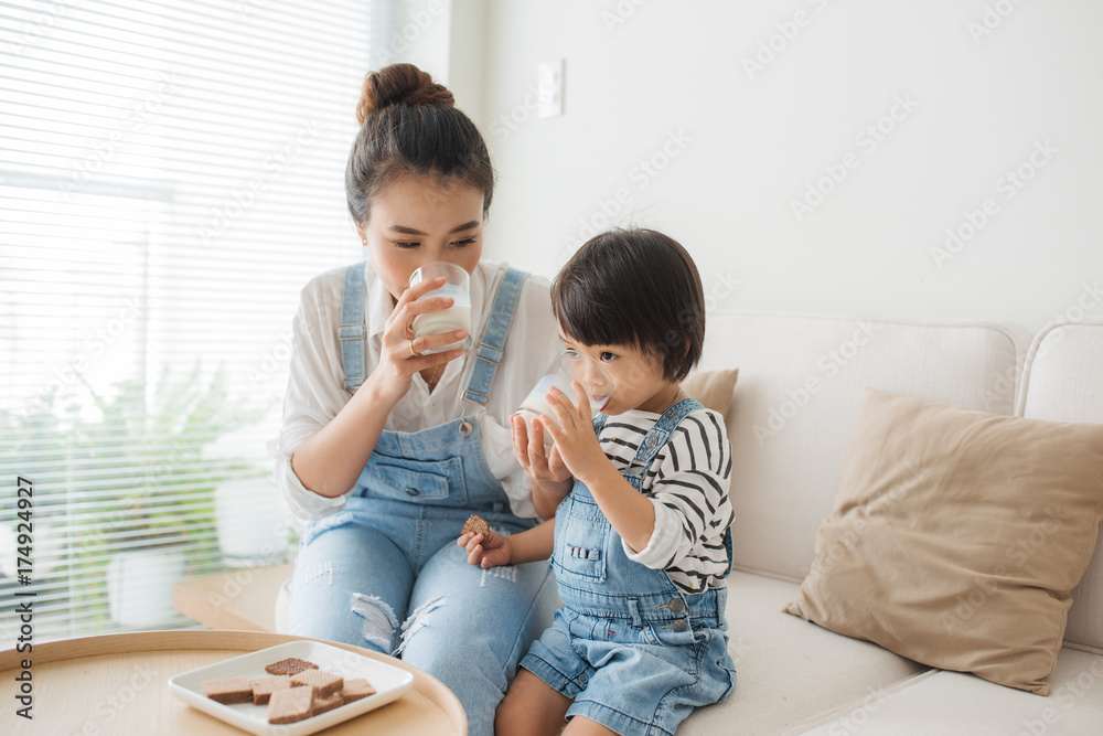 亚洲妈妈的幸福家庭早上在家和她可爱的女儿一起喝牛奶