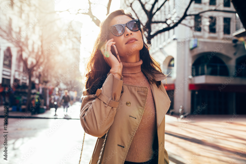 Fashionable female walking on street using phone