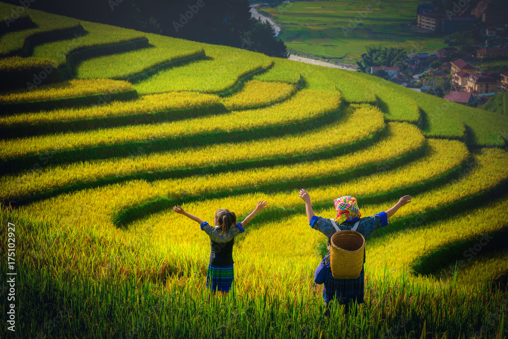 Women farmer and daughter raising armม  on Rice fields terraced at sunset in Mu Cang Chai, YenBai, V