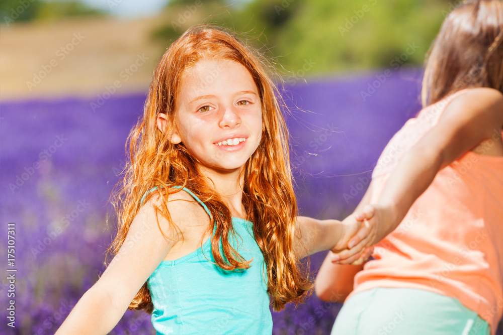 Happy girl walking with friend in lavender field